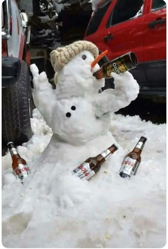 A snowman wearing a knit hat, with a carrot nose, holding a beer bottle in its twig arm, and several beer bottles scattered around in the snow.