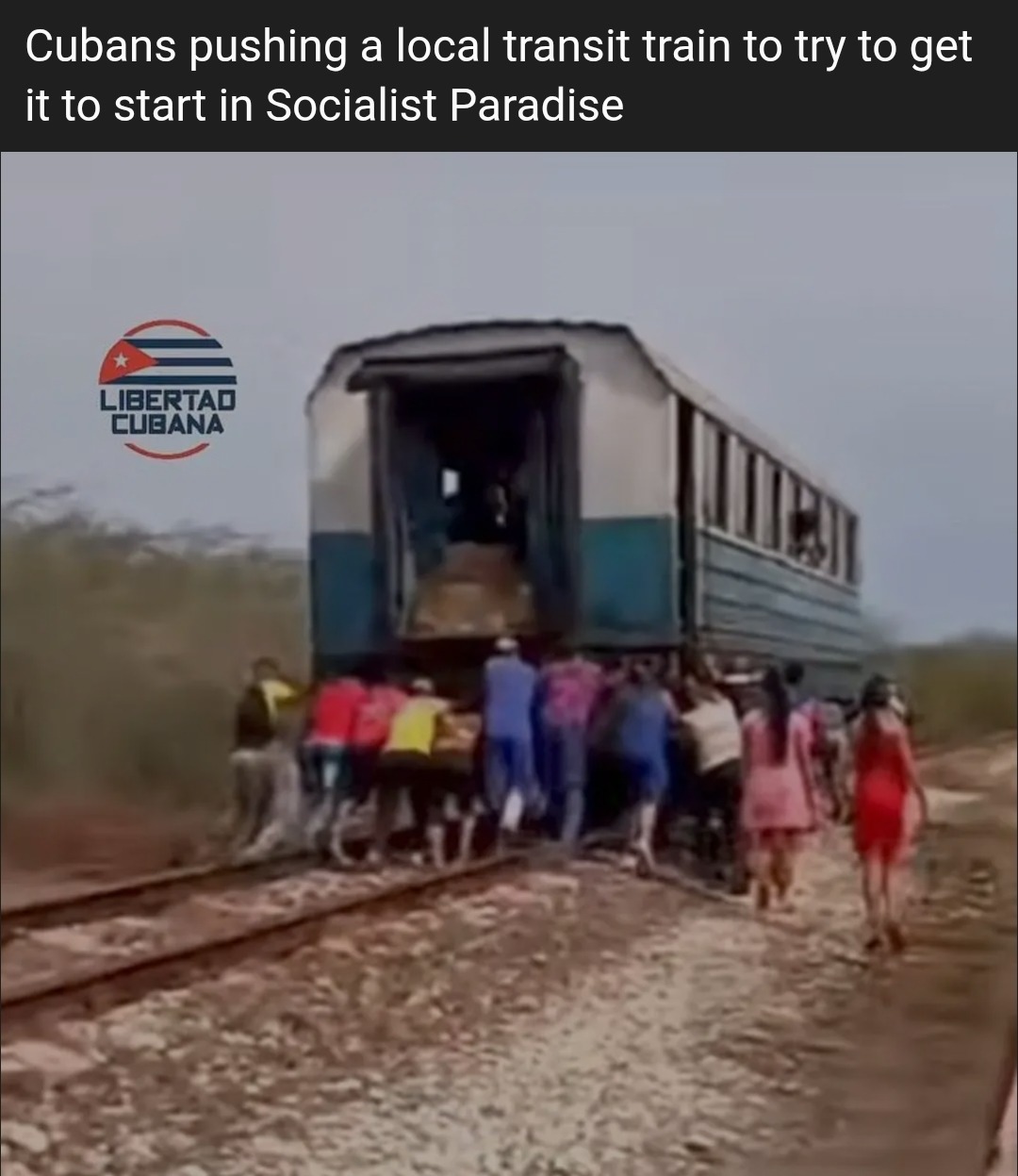 Cubans pushing a local transit train to try to get it to start in Socialist Paradise