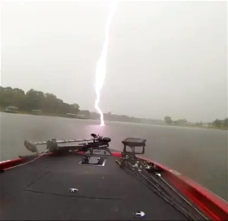 Lightning strike hitting near a boat on a lake
