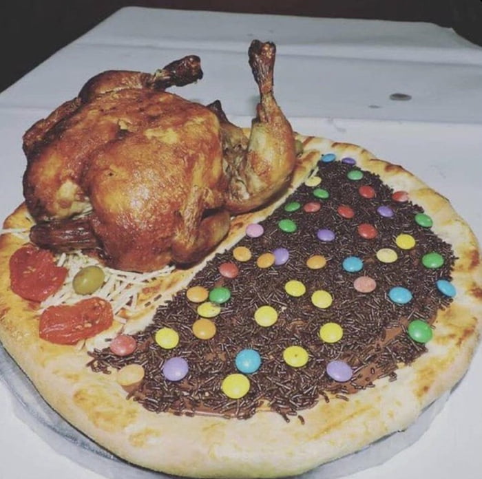Um frango assado inteiro colocado sobre uma pizza dividida em duas metades: uma salgada com queijo, azeitonas e tomate, e outra doce com cobertura de chocolate, granulado e confeitos coloridos.