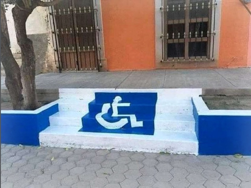 An accessibility symbol (person in a wheelchair) is painted on a set of stairs.