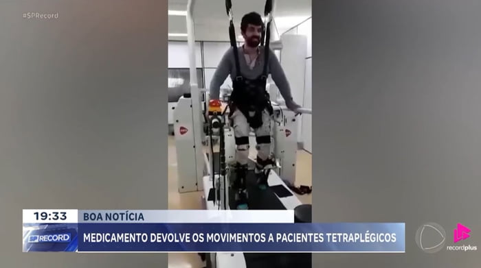 BOA NOTÍCIA MEDICAMENTO DEVOLVE OS MOVIMENTOS A PACIENTES TETRAPLÉGICOS. Um homem está usando um exoesqueleto ou dispositivo de reabilitação para caminhar em um ambiente clínico.