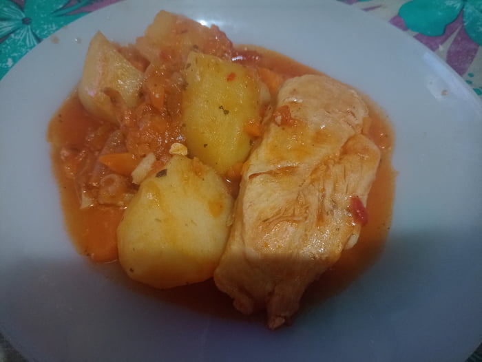 Un plato de pollo con patatas y salsa de tomate.