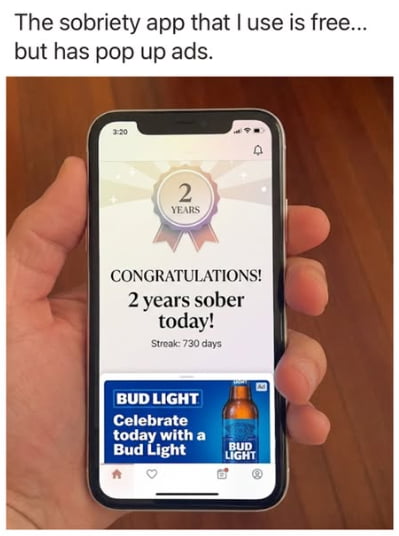 The sobriety app that I use is free... but has pop up ads. On the phone screen: 2 YEARS CONGRATULATIONS! 2 years sober today! Streak: 730 days. Below, an ad for BUD LIGHT: Celebrate today with a Bud Light.