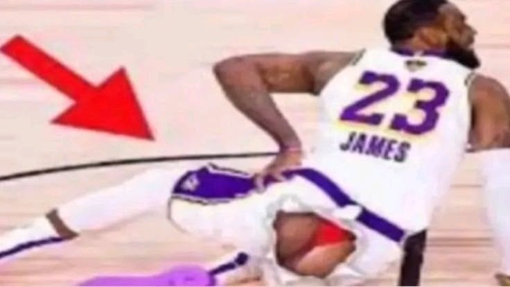 23 JAMES. Un jugador de baloncesto en el suelo con los pantalones bajados, revelando ropa interior roja. Una flecha roja apunta a la ropa interior.