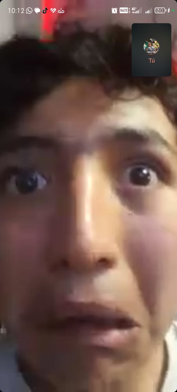 Una persona joven con una expresión de sorpresa o miedo, con los ojos muy abiertos y la boca ligeramente abierta, durante una videollamada. En la esquina superior derecha se ve una pequeña ventana con el texto 'Tú'.