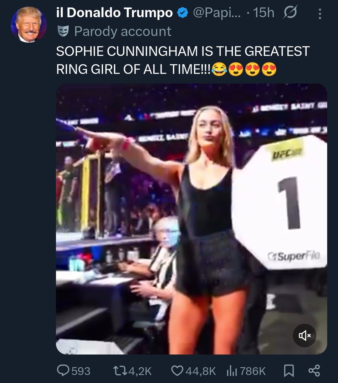 SOPHIE CUNNINGHAM IS THE GREATEST RING GIRL OF ALL TIME!!! A ring girl in a black top and shorts, holding a UFC sign with the number 1, pointing to the side in a sports arena.