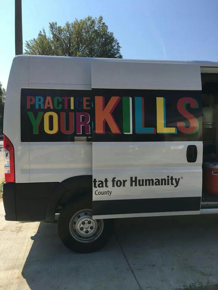 PRACTICE YOUR KILLS. The side of a white van displays the text 'PRACTICE YOUR' on its main body. Due to the sliding door being open, the word 'KILLS' is revealed on the main body, creating the phrase 'PRACTICE YOUR KILLS'. On the open sliding door, the text 'Habitat for Humanity® County' is visible.